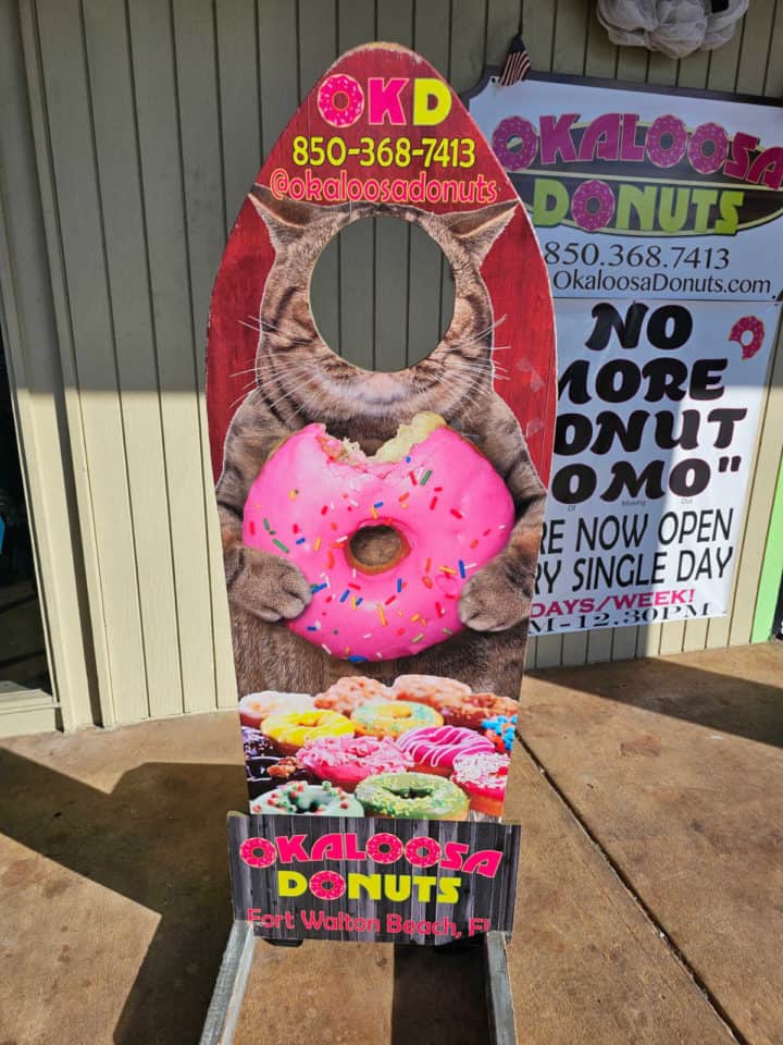 cut out sign with a cat face you can stick your head in and Okaloosa Donuts