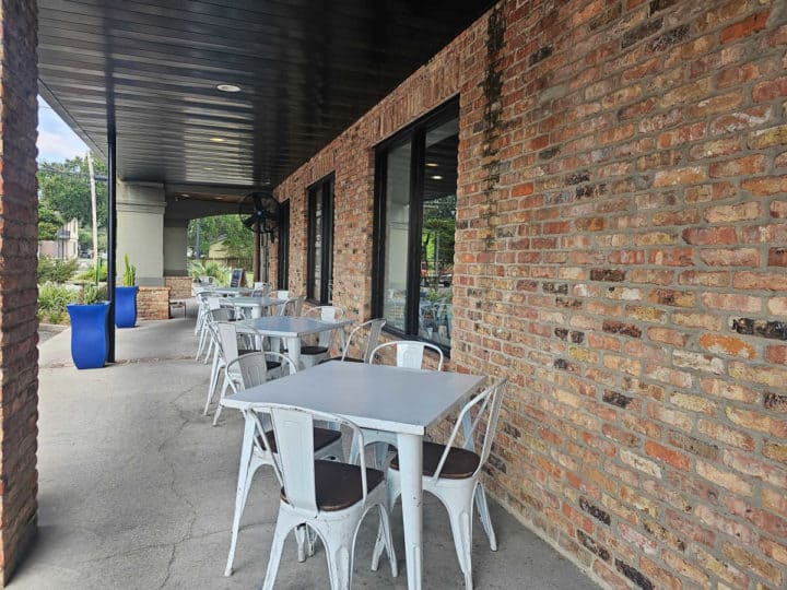 Outdoor tables next to a brick wall and walkway