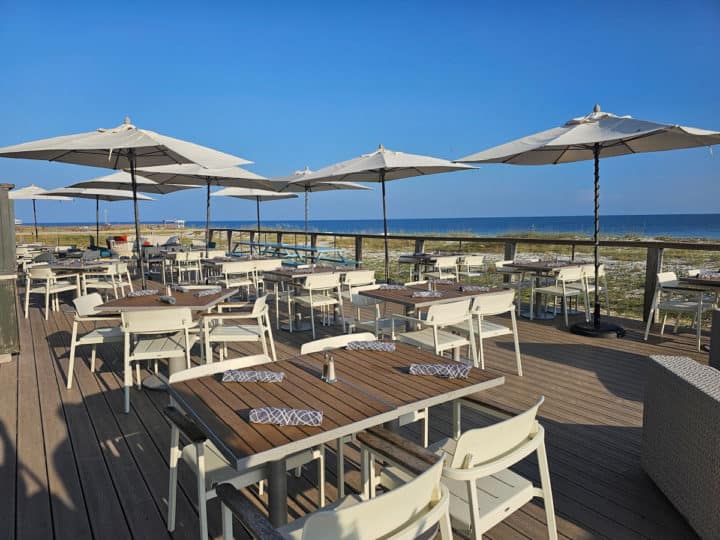 outdoor tables and chairs with umbrellas on a deck with views of the ocean