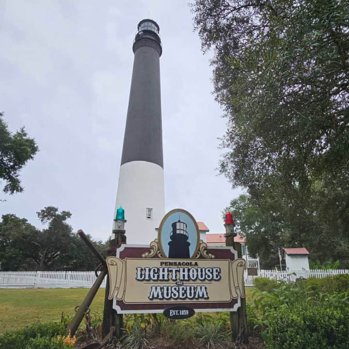 Pensacola Lighthouse & Museum sign below a black and white lighthouse