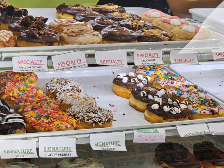 donuts lined on white trays in a bakery case