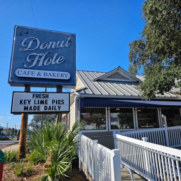 The Donut Hole sign next to a building with a white ramp and large tree