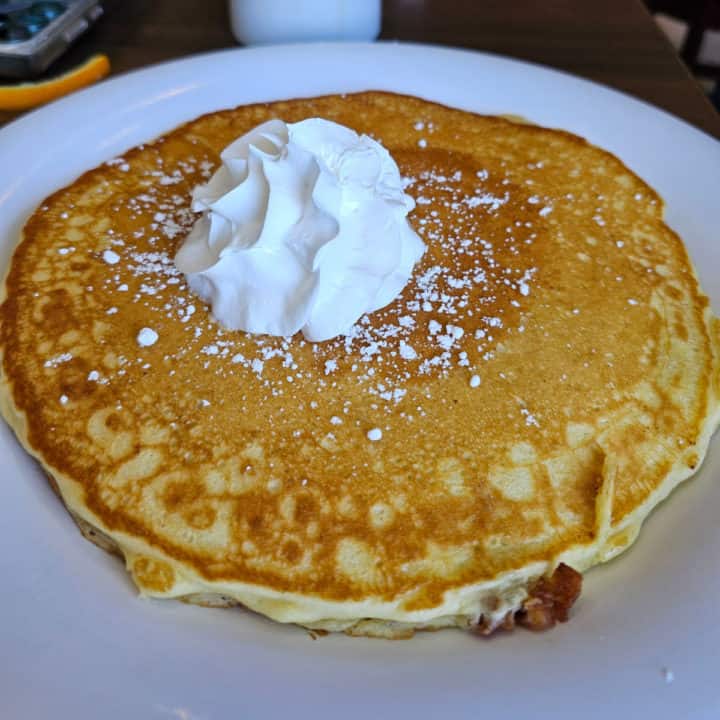 Large pancake with a dollop of whipped cream on a white plate