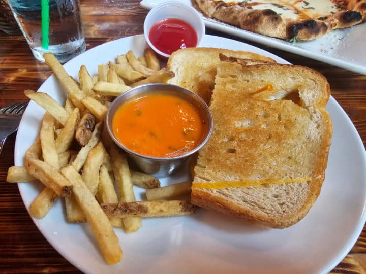grilled cheese and tomato soup with french fries on a white plate