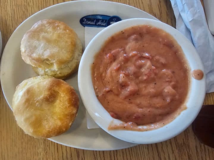 tomato gravy in a white bowl next to biscuits