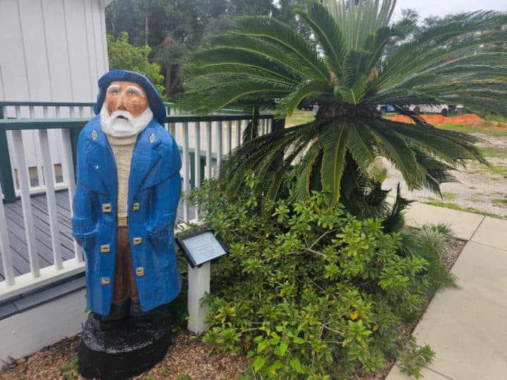 lightkeeper statue next to a small palm tree