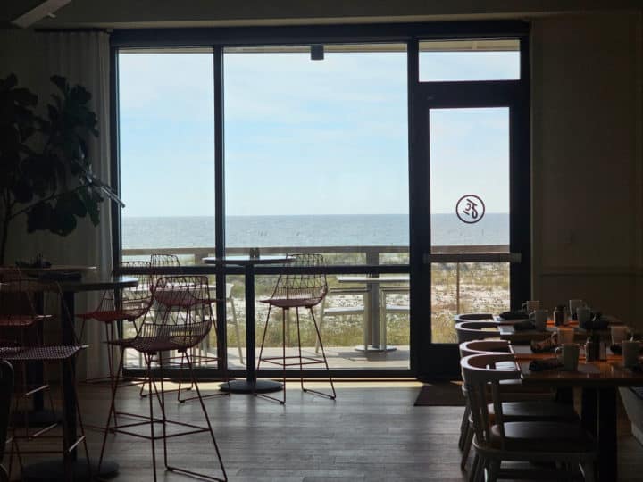 ocean views through a restaurant large window with tables and chairs near the window