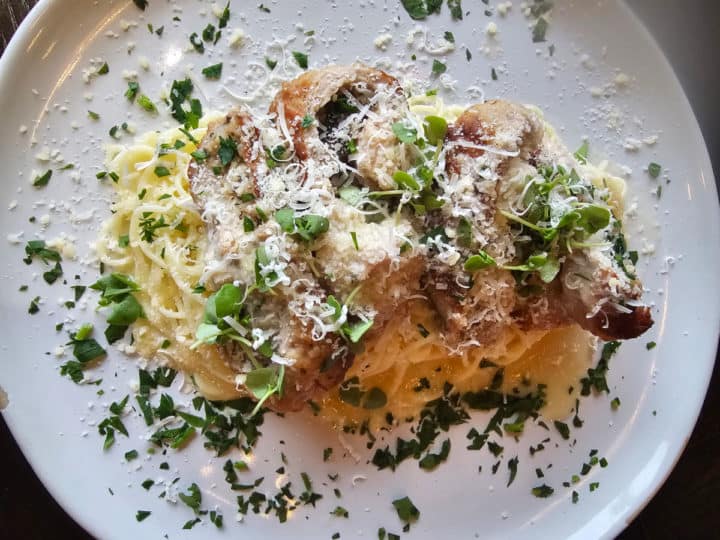 angel hair pasta with veal stuffed prosciutto and cheese on a white plate