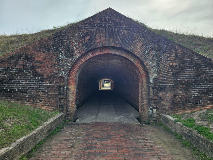 brick tunnel with grass growing over it leading into the fort