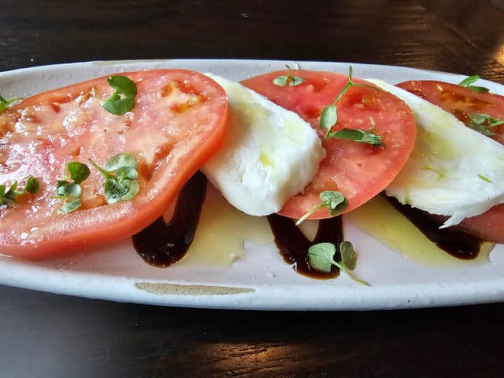 caprese salad with tomatoes, mozzarella and balsamic vinegar on a white platter