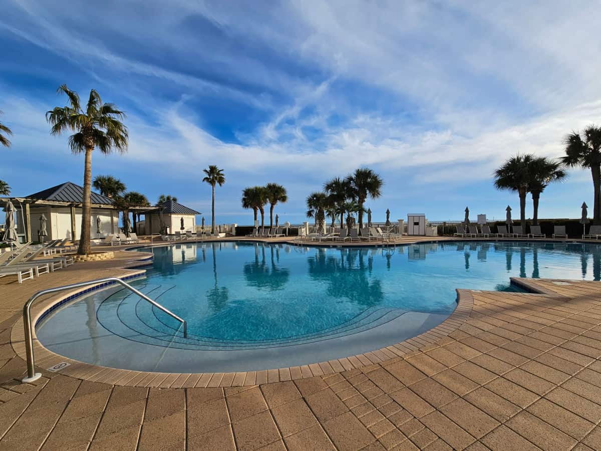outdoor pool with palm trees reflecting in the water