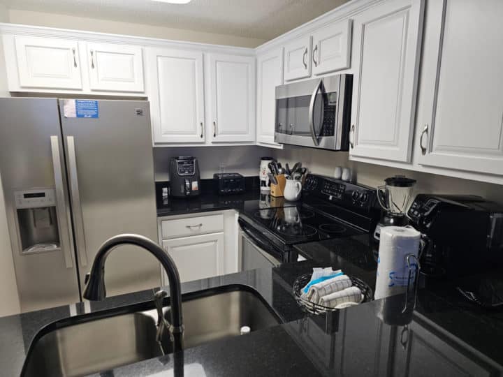 Condo kitchen with cabinets, fridge, microwave, sink, and more
