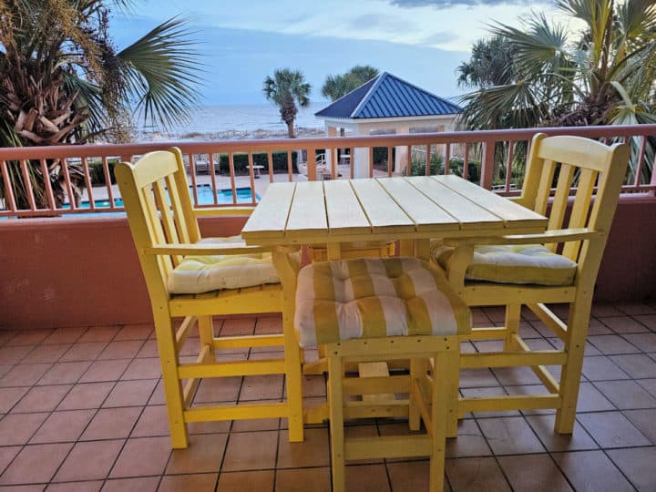 yellow tables and chairs on a deck looking out to a pool and the open water