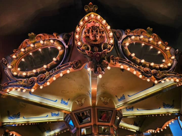 light up top of a carousel with a face carved into it