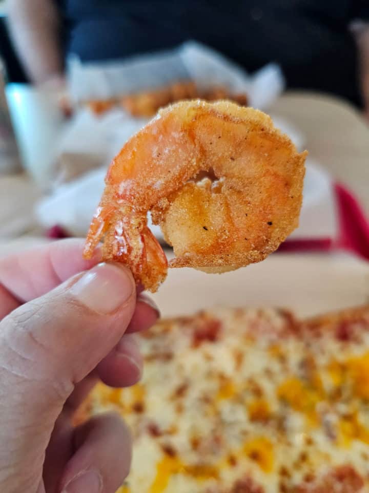 hand holding a piece of fried shrimp