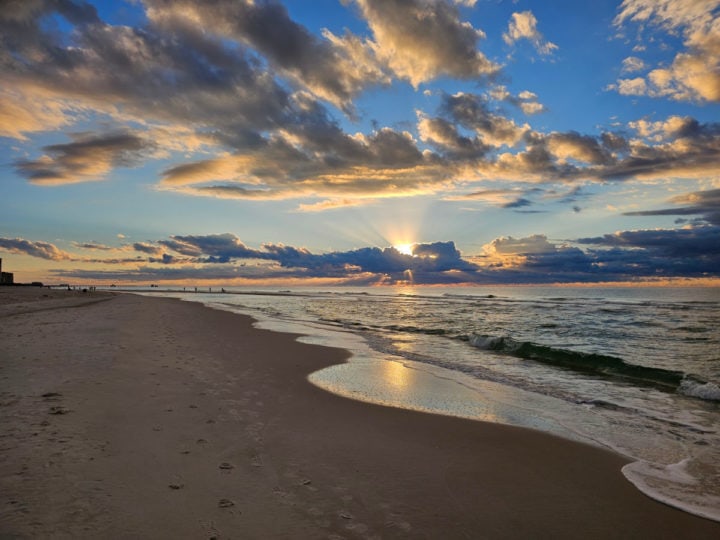 sunrise over the beach with clouds in the sky