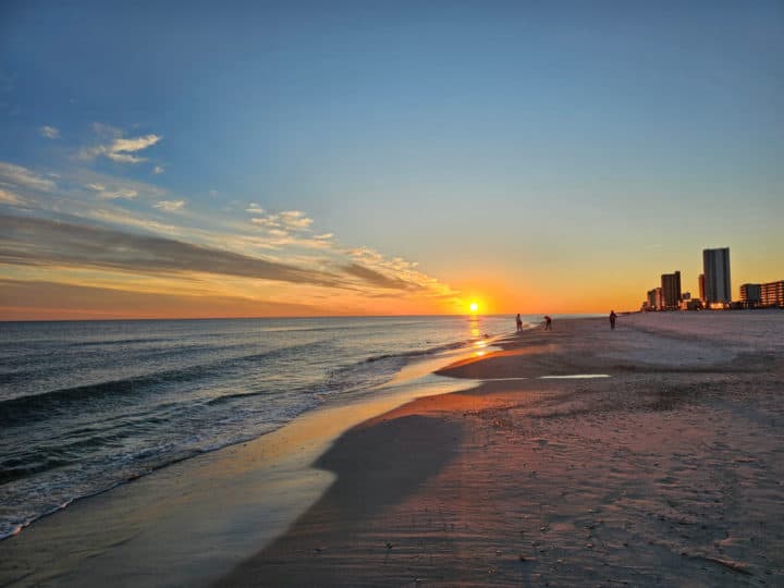 sunset over the beach with a few hotels and buildings to the side