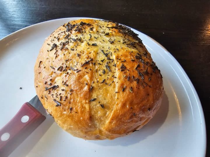 Herb bread on a white plate with a knife