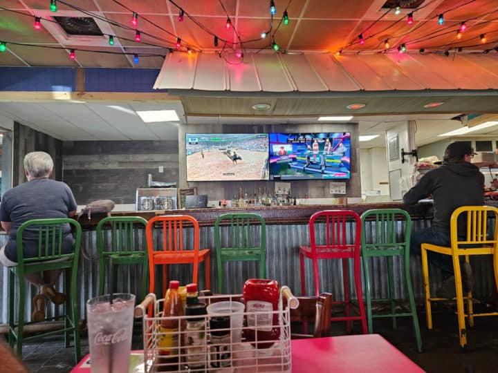 bar with colorful chairs, TVs playing in the background
