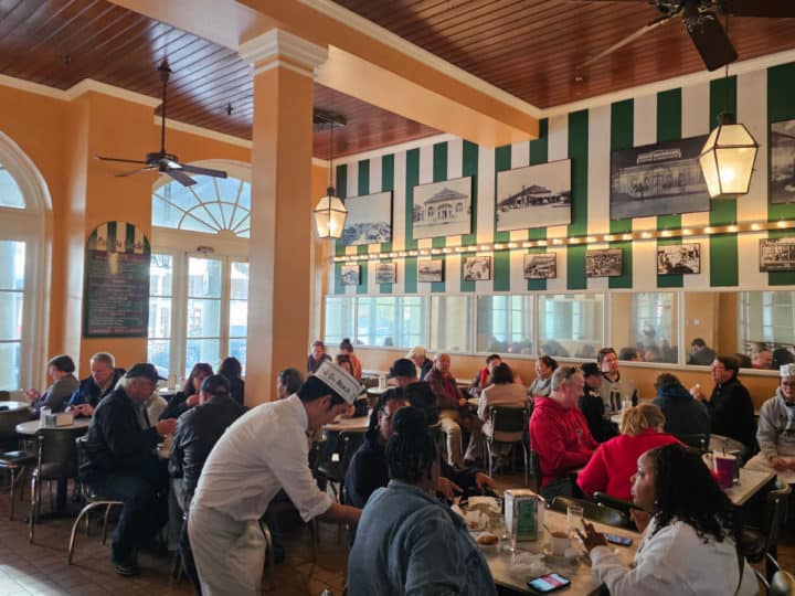 indoor tables and chairs in a room with green and white decorations and fans on the ceiling