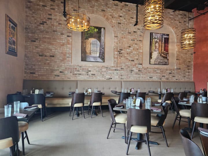 Tables and chairs inside the restaurant with chandeliers, a brick wall with art