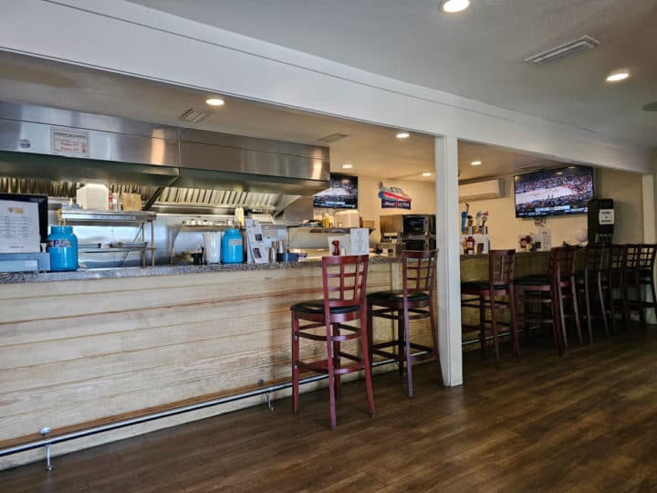 order counter and bar with tall chairs pulled up to the bar, tv on the wall