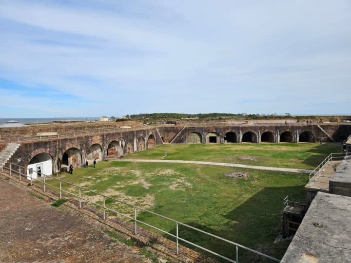 Looking over historic fort Morgan with a grassy field and brick structures 