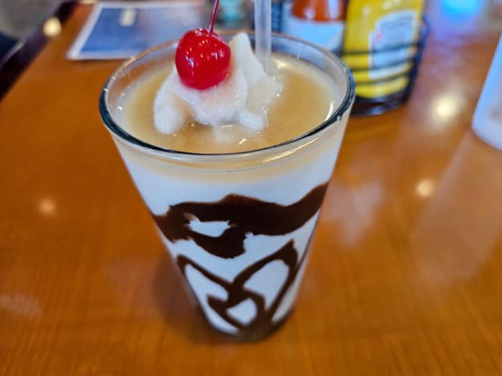 glass lined in chocolate syrup, frozen drink topped with whipped cream and a cherry