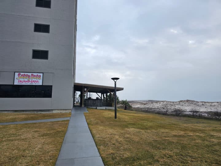 paved walkway to the entrance of a building with a Sassy Bass Island Grill Sign