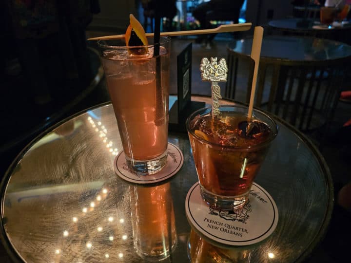 two cocktails with stir sticks on a mirrored table top