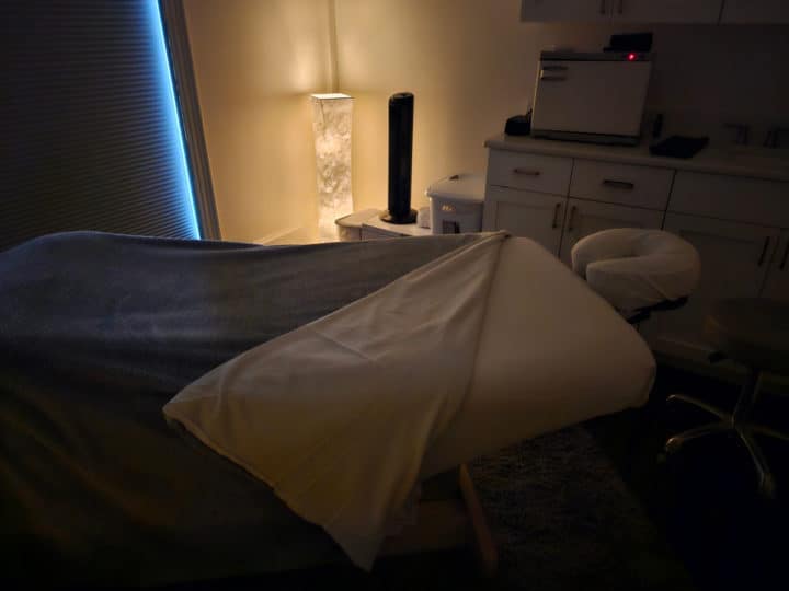 dark room with a single light, massage table, and cabinets