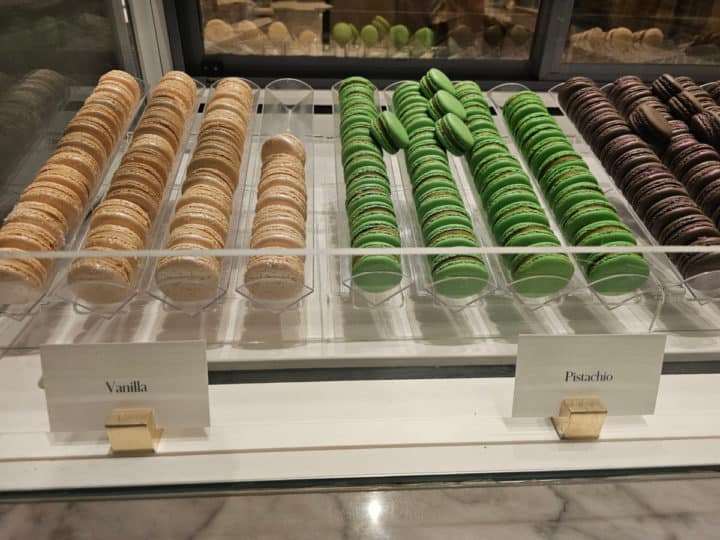 vanilla and pistachio macarons in a display case