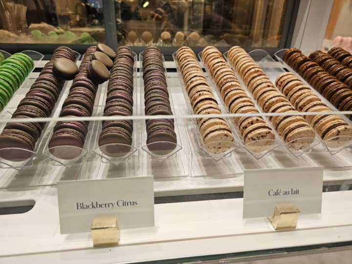 blackberry citrus and cafe au lait macarons on display in a case