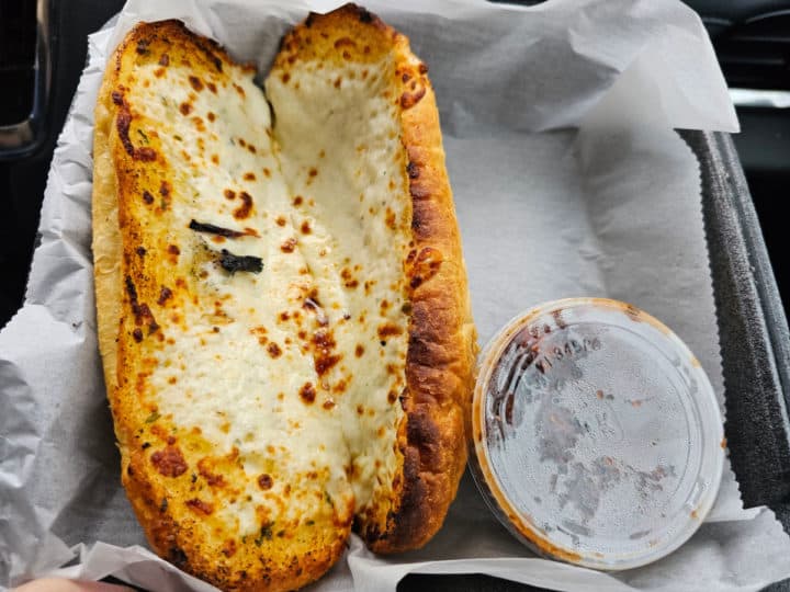 garlic cheese bread in a container with a bowl of marina sauce