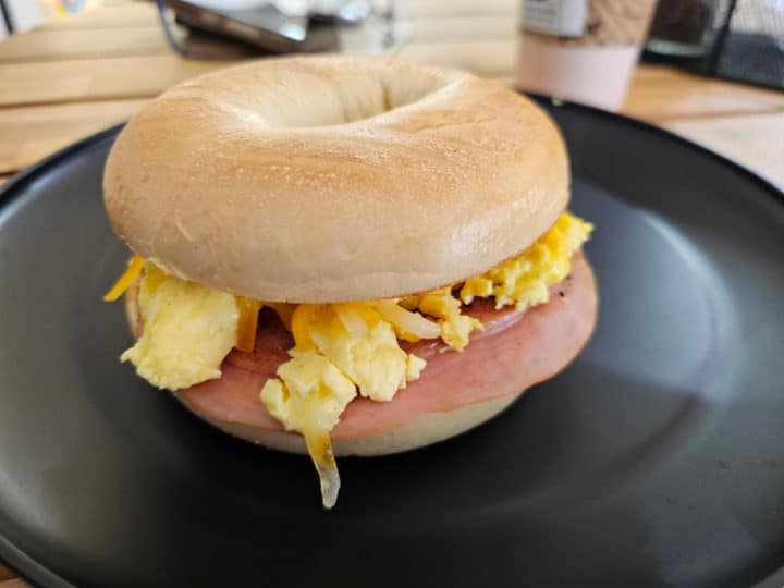 ham egg and cheese breakfast bagel on a dark plate