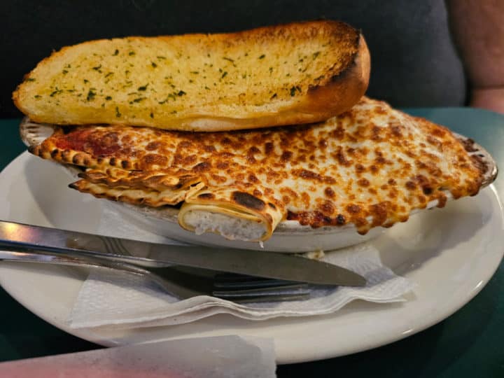 garlic bread on cheese pasta dish in a white bowl 