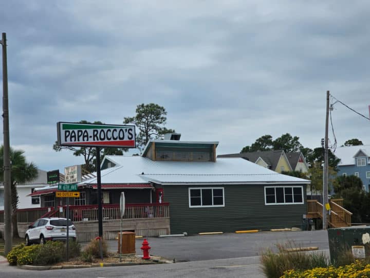 Papa Rocco's sign in front of a green building. 