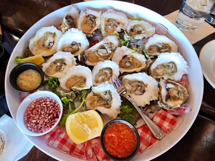 Raw oyster platter on a white large plate with condiments