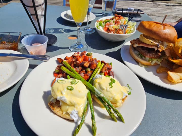 Brunch Eggs benedict and Brunch Burger near loaded tater tots, a mimosa and bread container 