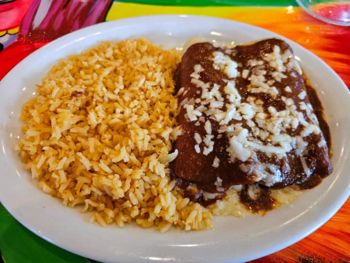 Cheese enchiladas next to rice on a white plate