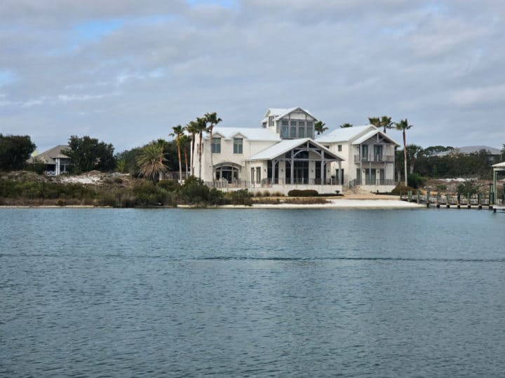 Large white house with a palm trees on Ono Island seen from the water
