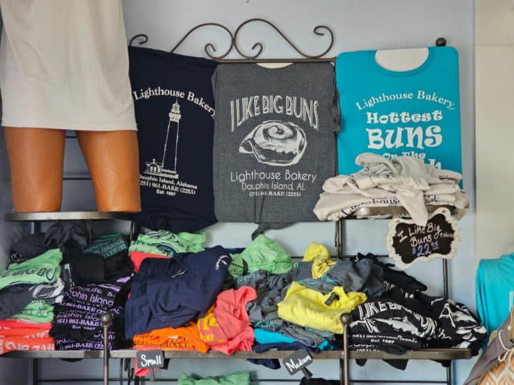 Lighthouse bakery t-shirts on display with some in piles 