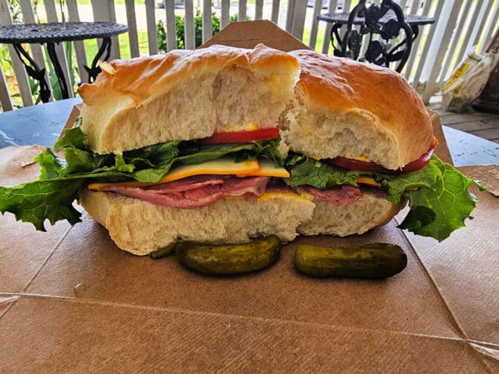 large hoagie with meat, lettuce, tomato, and cheese on a paper box. 