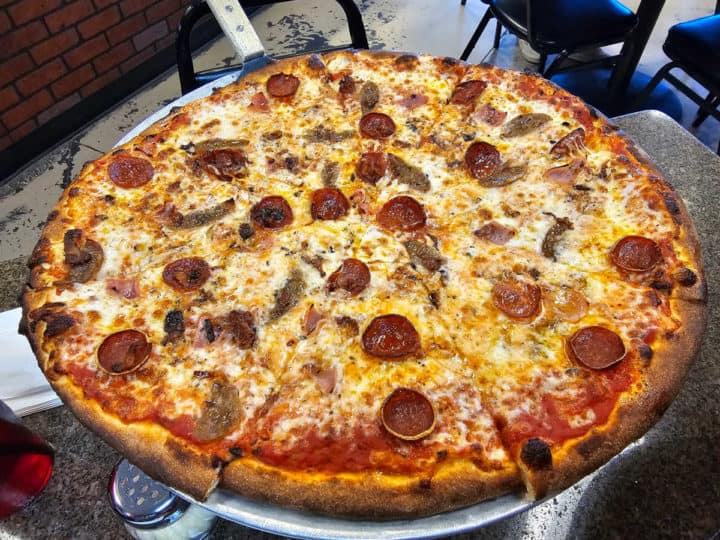 meat covered pizza with cheese on a pizza pan