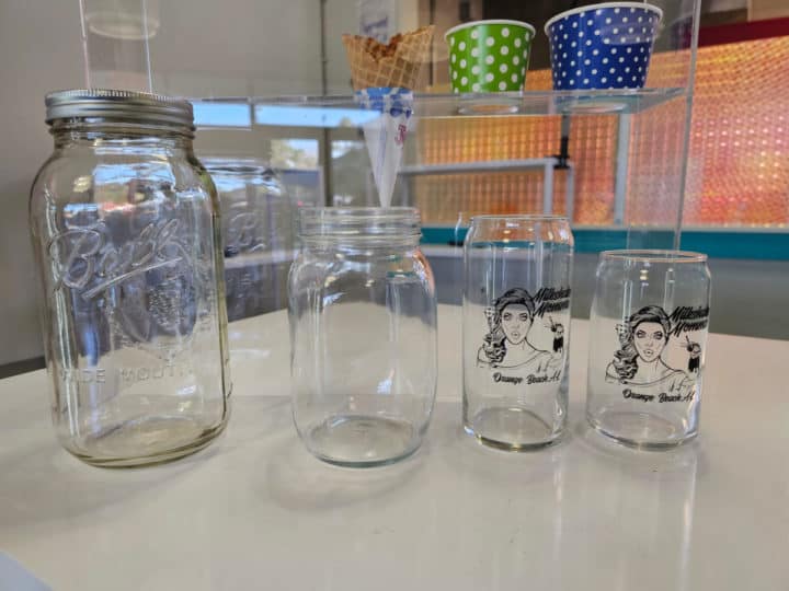 Four different size glasses with two mason jars and two glasses with the Milkshake Momma logo on them. 