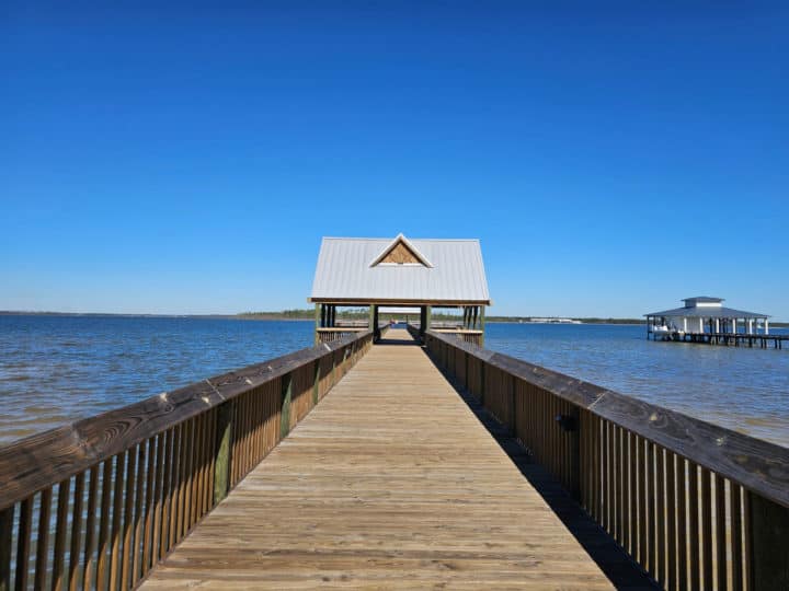 Long wooden pier with a covered area at the end. Blue skies with no clouds