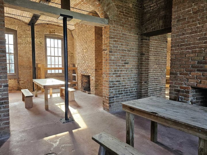 wooden tables and chairs inside Fort Gaines with brick walls