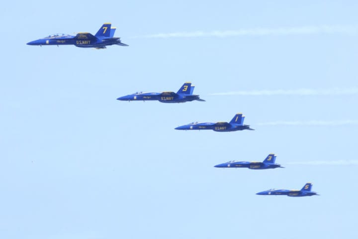 Five Blue Angels jets fly in a line with smoke trailing