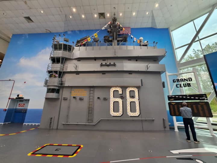 Aircraft Carrier replica inside the museum with person standing at a sign