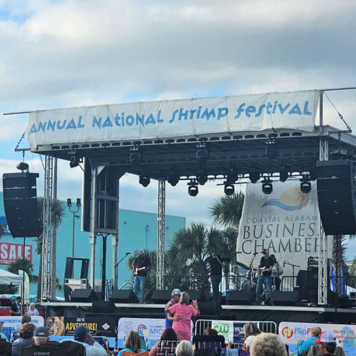 Annual National Shrimp Festival main stage with a band performing and people in chairs watching and a couple dancing. 